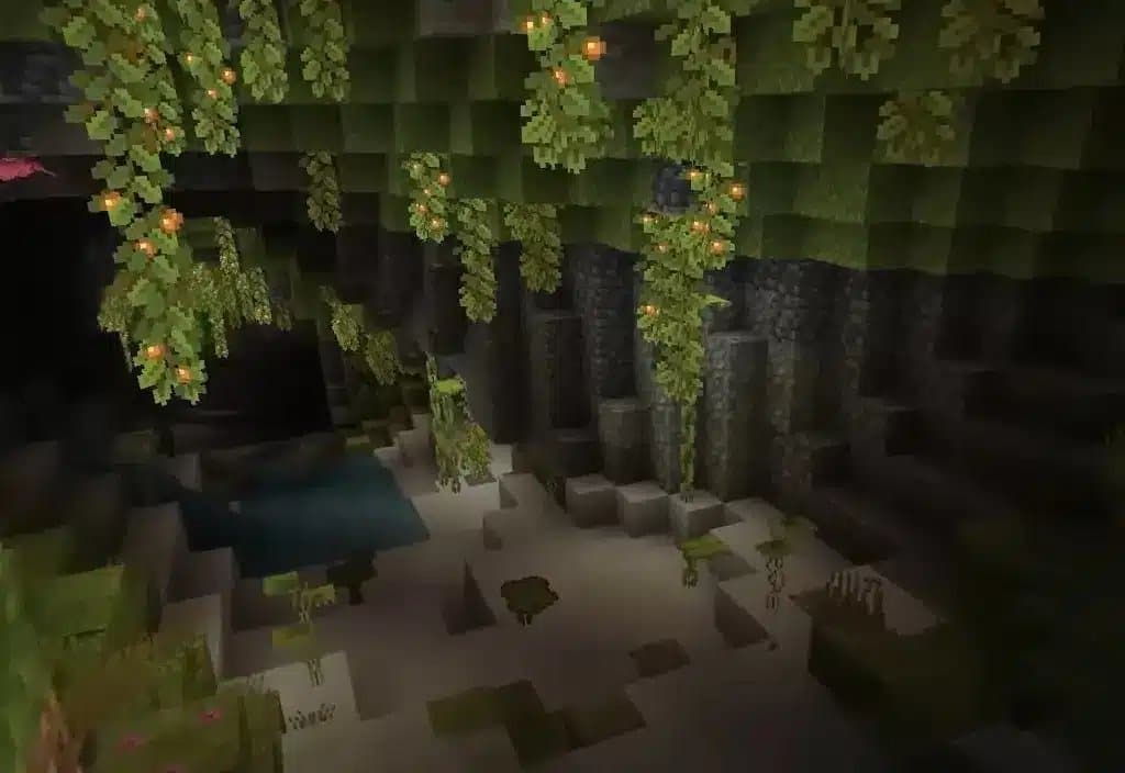 Vue d'un biome Lush Caves dans Minecraft, avec des baies lumineuses suspendues et de la verdure.